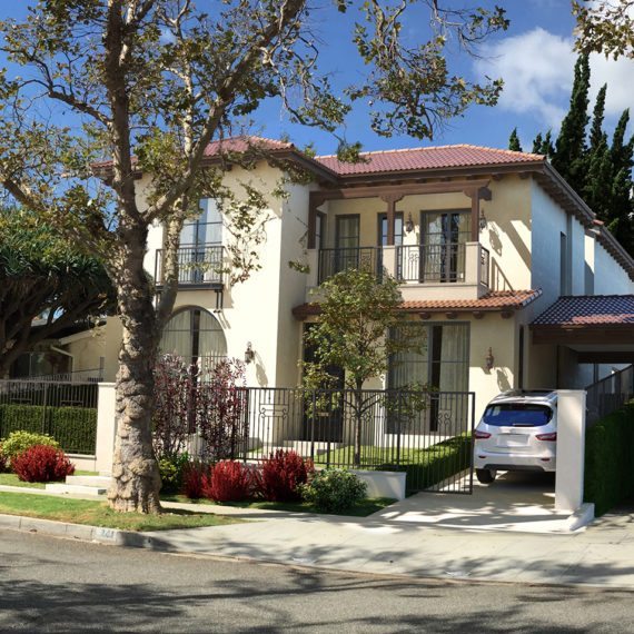 Two-story house with trees and a parked car in the driveway.