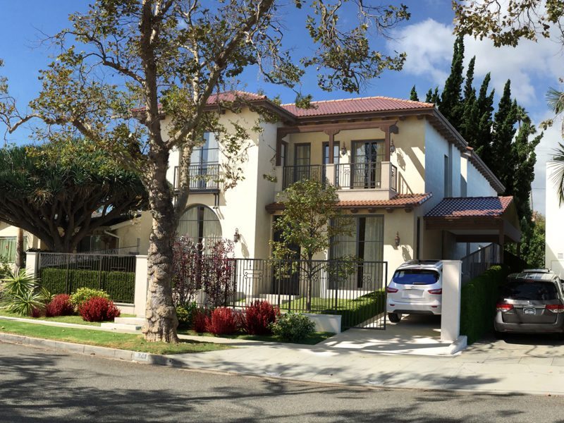 Two-story house with trees and a parked car in the driveway.