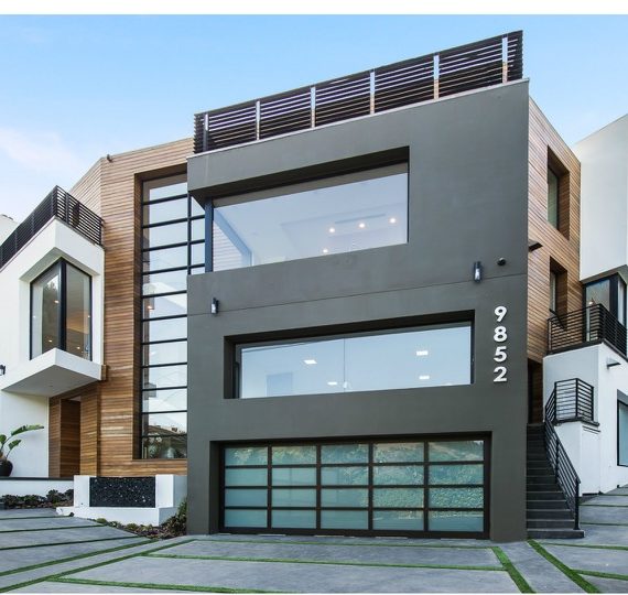 Modern three-story house with large glass windows and sleek design.