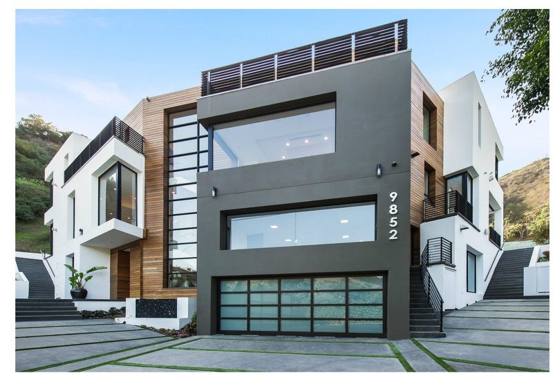 Modern three-story house with large glass windows and sleek design.