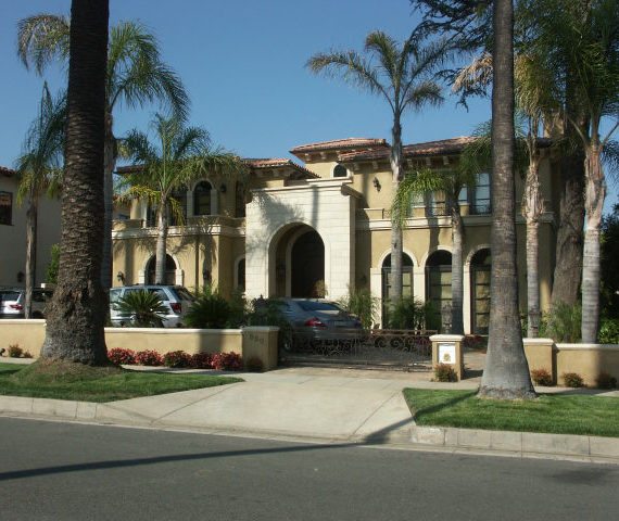 Elegant Mediterranean-style building with palm trees and a fountain.