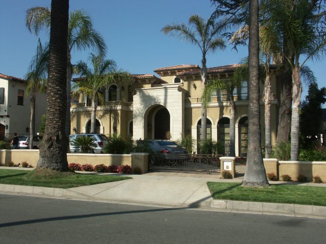 Elegant Mediterranean-style building with palm trees and a fountain.