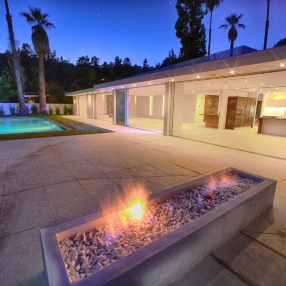 Modern backyard with a fire pit and pool at dusk.
