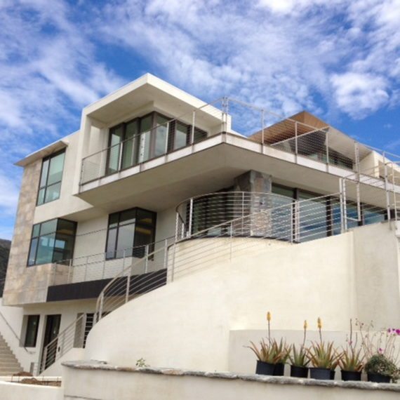 Modern multi-story building with large windows and balconies under a blue sky.