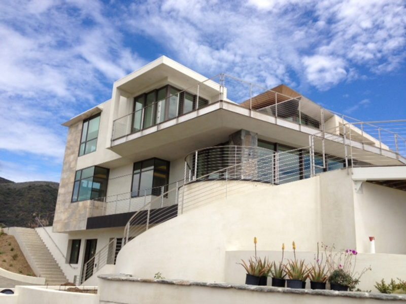 Modern multi-story building with large windows and balconies under a blue sky.