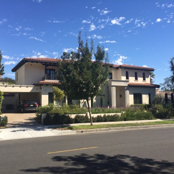 Modern two-story house with a well-maintained front yard and clear blue sky.
