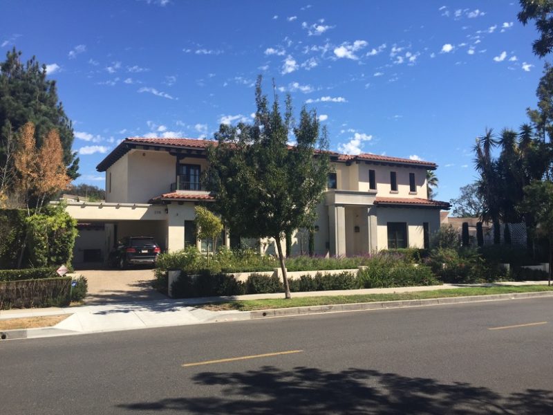 Modern two-story house with a well-maintained front yard and clear blue sky.
