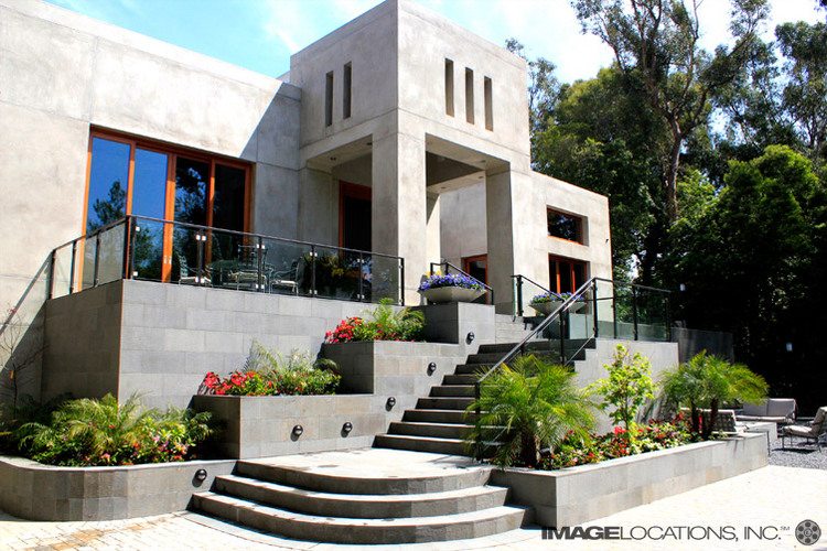 Modern stone house with large windows and a grand staircase.