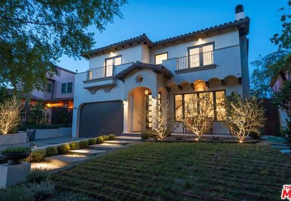 A modern two-story house illuminated at dusk with a neatly manicured lawn.