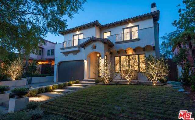 A modern two-story house illuminated at dusk with a neatly manicured lawn.