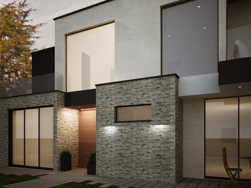 Modern townhouse exterior with stone and stucco walls illuminated at night.