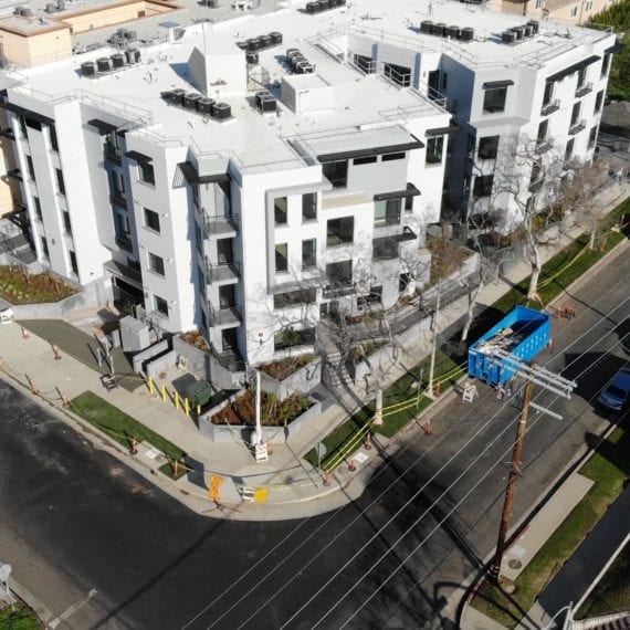 Modern apartment complex with green landscaping and surrounding roads.