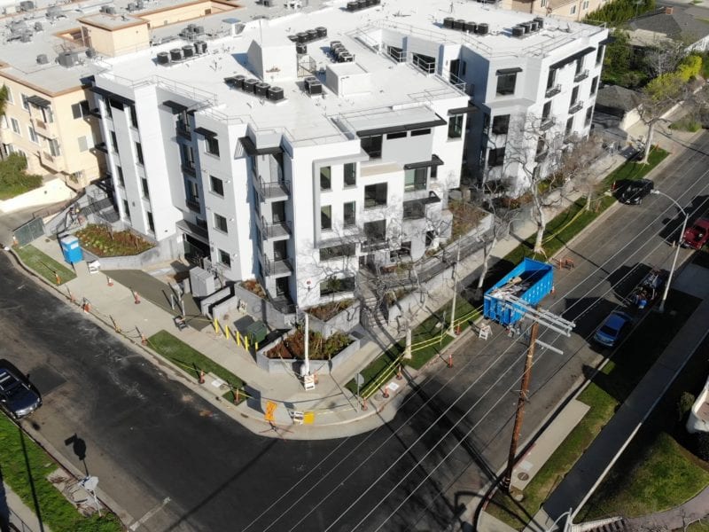 Modern apartment complex with green landscaping and surrounding roads.