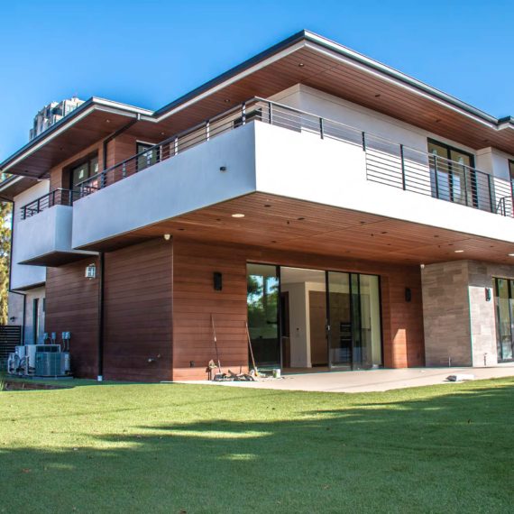Modern two-story house with wooden accents and a spacious lawn.