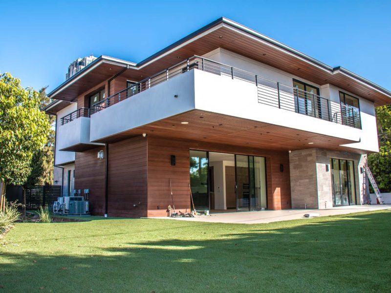 Modern two-story house with wooden accents and a spacious lawn.