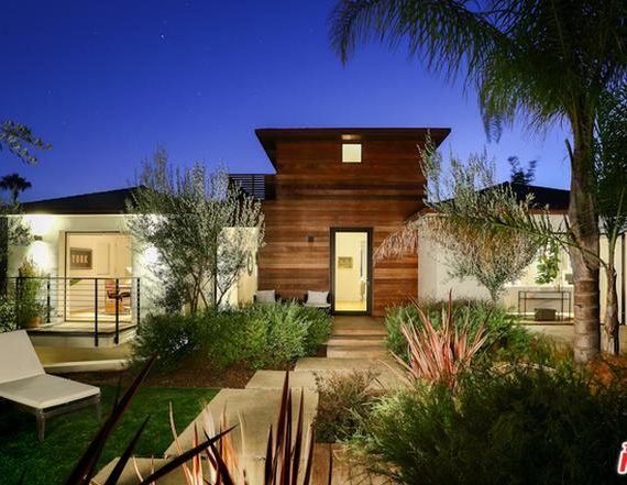 Modern house with warm lighting and landscaped garden at night.