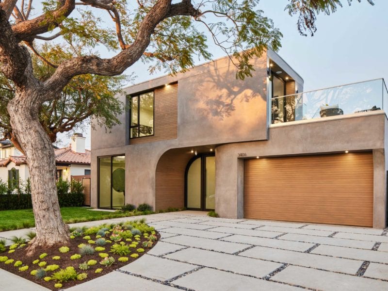 Modern two-story house with a large garage and landscaped yard.