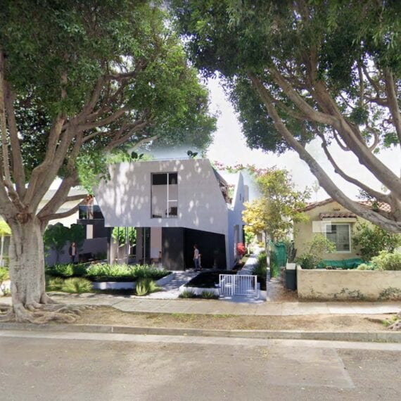 Modern house under large trees on a sunny day.